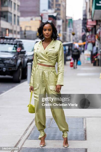 Ciara Miller wears mint green pants, cropped top, bag, plexiglas heels outside Bronx & Banco during New York Fashion Week on February 12, 2023 in New...