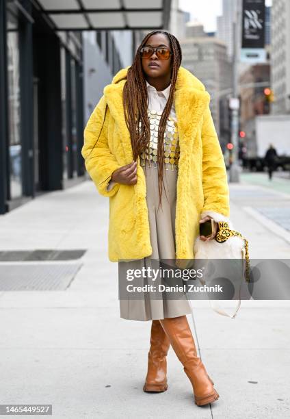 Akinyi is seen wearing an Apparis yellow faux fur coat, gold Misguided top, tan skirt and brown boots with a faux fur bag outside the Chiara Boni...