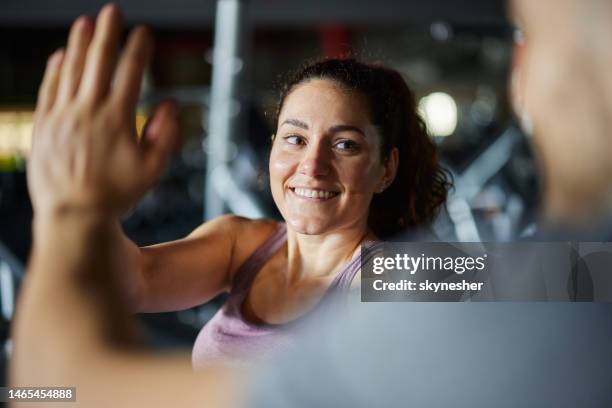 donna atletica felice che dà al suo amico il cinque durante una pausa in palestra. - hi five gym foto e immagini stock