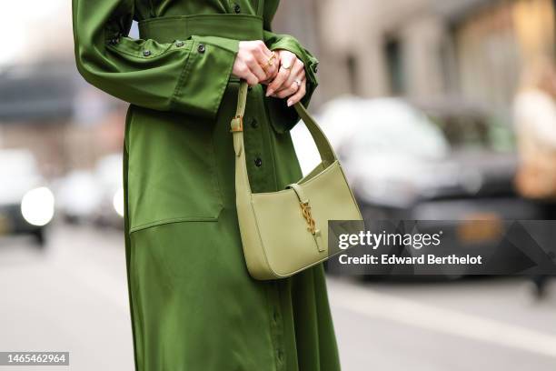 Victoria Magrath wears a green silk long sleeves / large belted / long dress, a pale green shiny leather handbag from Saint Laurent Paris , outside...