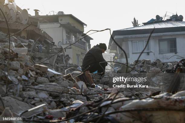 Man sits on top of a collapsed buinding on February 13, 2023 in Hatay, Turkey. A 7.8-magnitude earthquake hit near Gaziantep, Turkey, in the early...