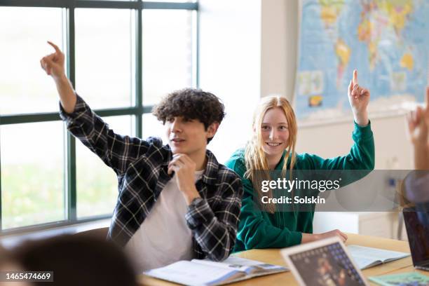 teenage students in classroom, hands raised - onderwijsinstituten en organisaties stockfoto's en -beelden