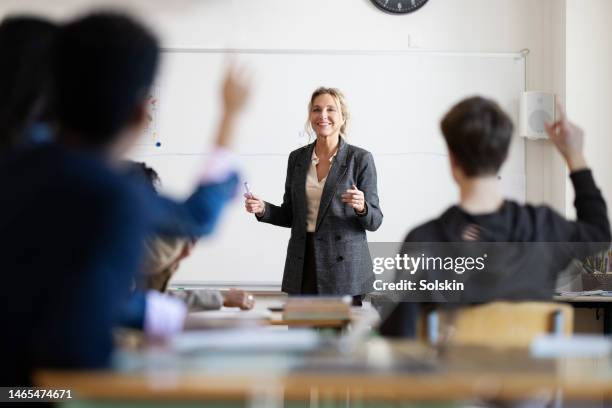 female teacher in classroom standing by whiteboard - lärare bildbanksfoton och bilder