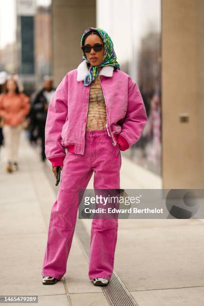 Guest wears black sunglasses, a green / yellow print pattern silk scarf, a beige with brown print pattern tie and dye t-shirt, a pink denim with...