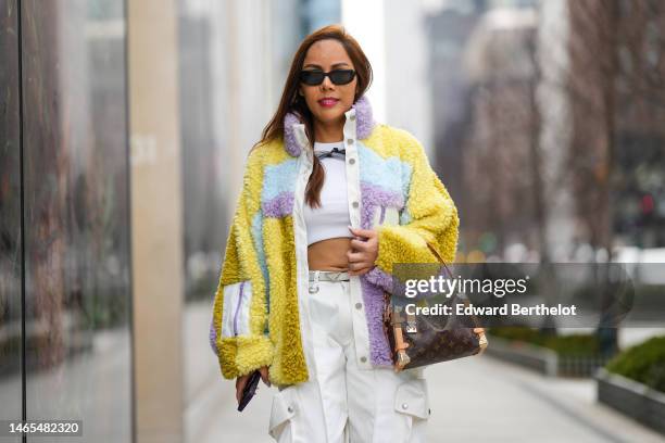 Guest wears black sunglasses, a white cropped top, a black tulle necklace, a pale purple / blue / yellow fluffy oversized jacket, a brown LV monogram...