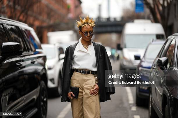 Guest wears black sunglasses, gold and silver chains necklaces, a white polo shirt, a black shiny leather blazer jacket, a black shiny leather belt,...