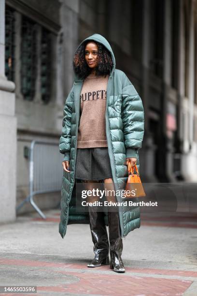 Guest wears a dark green hoodie / shoulder fabric / quilted nylon long puffer jacket, a dark brown with embroidered black pattern sweater, a black...