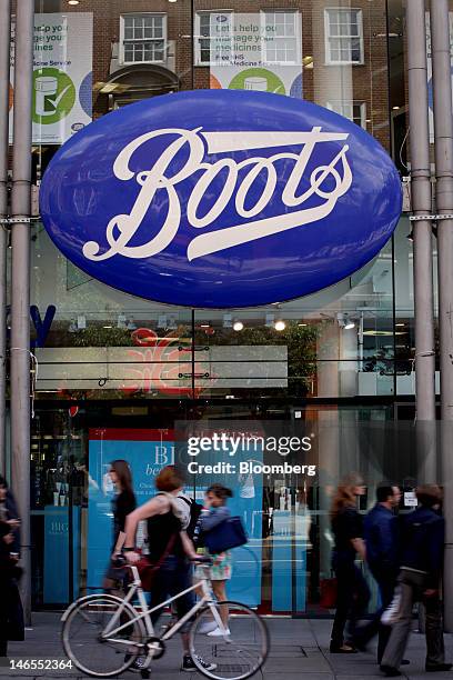 Cyclist wheels her bicycle past a Boots store, operated by Alliance Boots, in London, U.K., on Tuesday, June 19, 2012. Walgreen Co., the largest U.S....