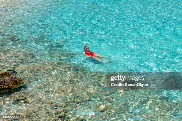 woman in red swimsuit swimming in the clear sea. - mugla province stock pictures, royalty-free photos & images