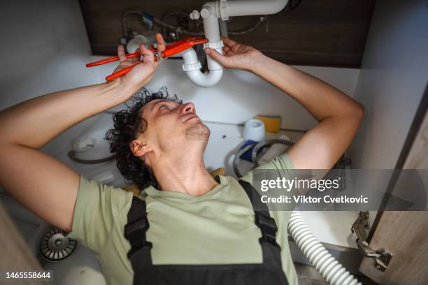 plumber fixing a problem with water pipes under kitchen sink - looking under sink stock pictures, royalty-free photos & images