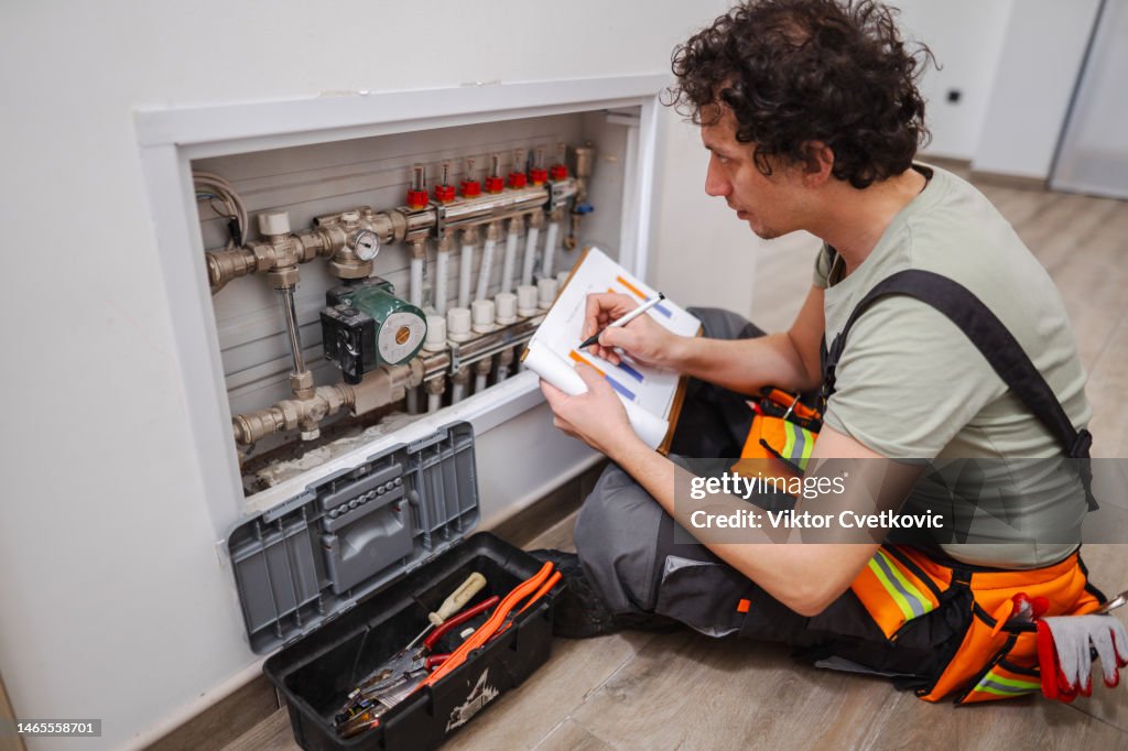 Reparateure, die einen Bericht schreiben, nachdem sie ein Problem mit Fußbodenheizungsrohren gelöst haben