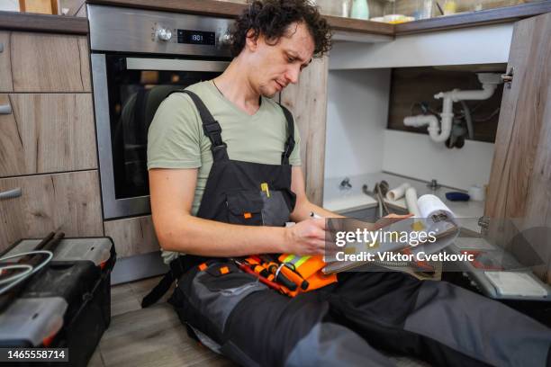 plumber looking into plumb line scheme before fixing them - looking under sink stock pictures, royalty-free photos & images