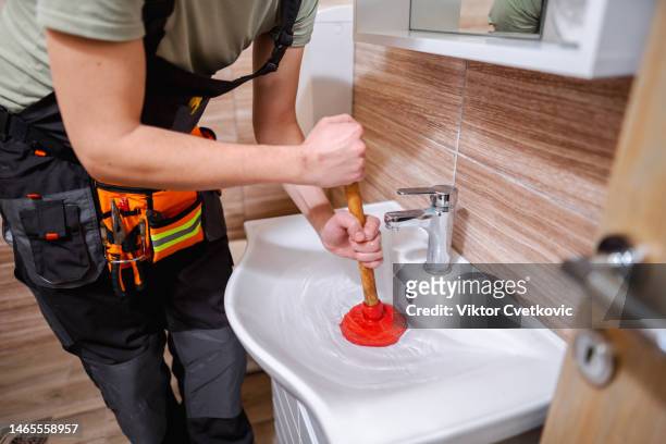 plumber fixing clogged bathroom sink with plunger - plunger stock pictures, royalty-free photos & images