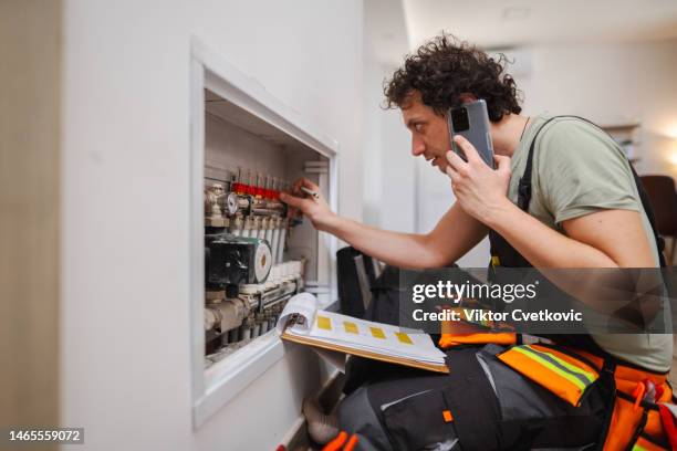 repairmen calling colleague for advice about a problem with underfloor heating pipes - plumber stock pictures, royalty-free photos & images