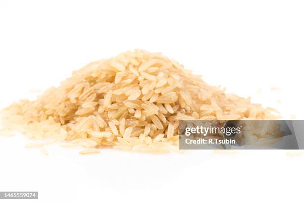 pile of brown rice isolated on a white background - naturreis stock-fotos und bilder