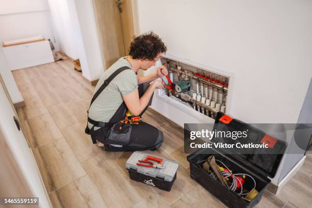 repairmen fixing a problem with underfloor heating pipes - heating home stock pictures, royalty-free photos & images