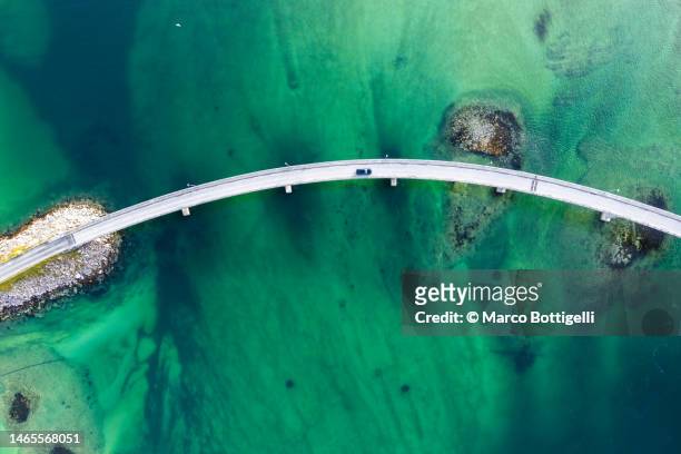 car driving on bridge over emerald green water - northern norway stock-fotos und bilder