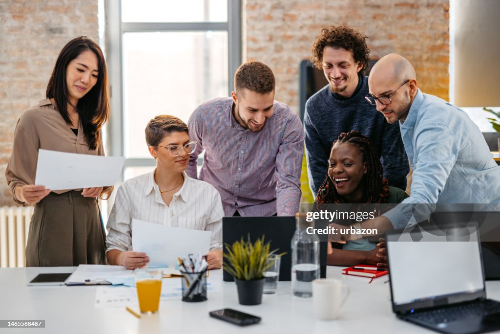 Colleagues Watching Something On Laptop While At The Office