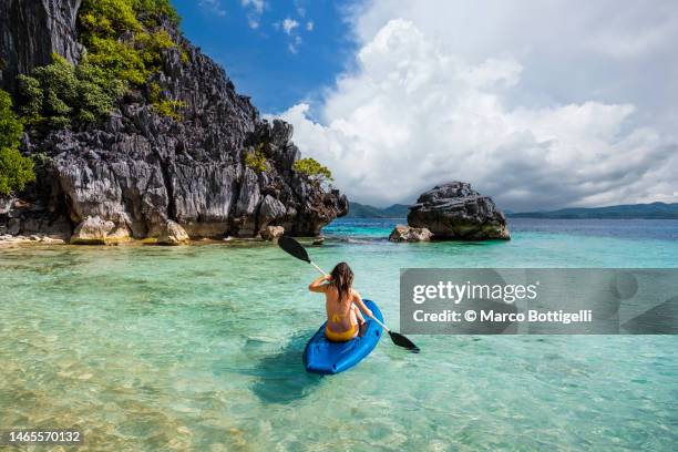 woman kayaking to a beach hut in palawan, philippines. - philippines women fotografías e imágenes de stock