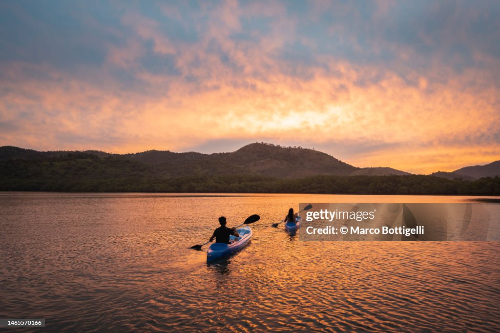 Two people kayaking in a lagoon at sunset