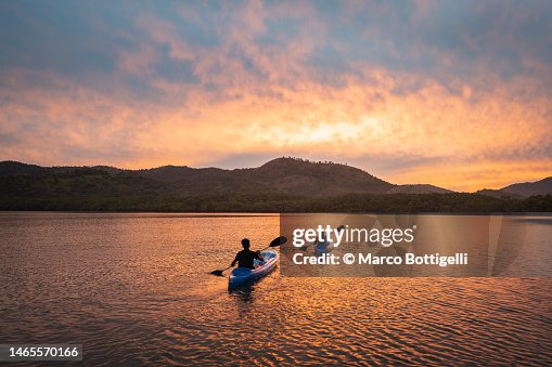 Two people kayaking in a lagoon at sunset Two people kayaking in a lagoon at sunset