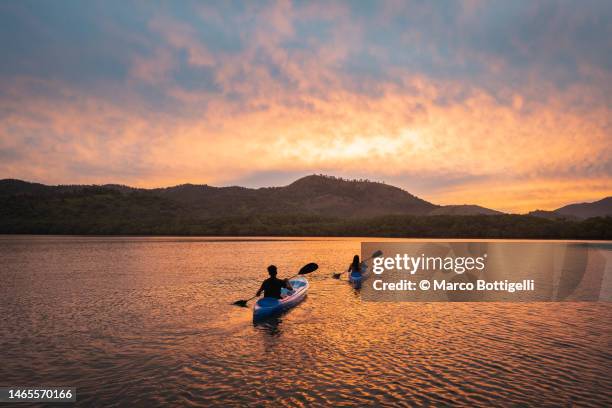 two people kayaking in a lagoon at sunset - the glory of water karl lagerfelds exhibition dinner outside arrivals at fendi stockfoto's en -beelden