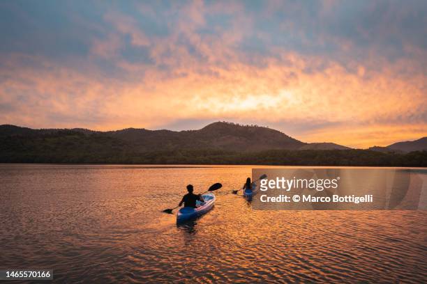 two people kayaking in a lagoon at sunset - kayaking stock pictures, royalty-free photos & images