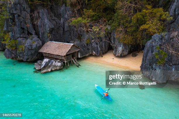 woman kayaking to a beach hut in palawan, philippines - filippino foto e immagini stock