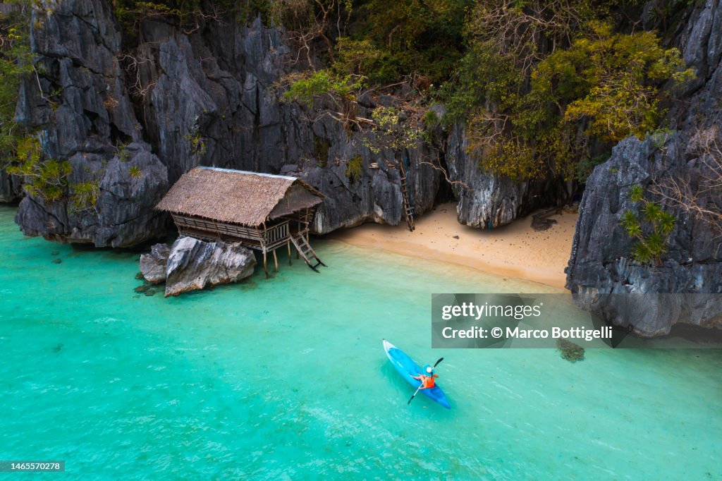 Woman kayaking to a beach hut in Palawan, Philippines