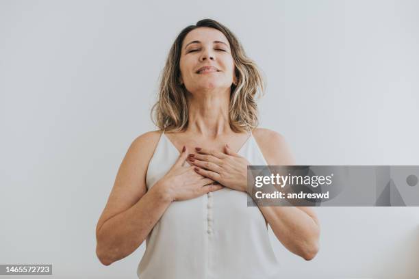 portrait of a mature woman breathing with her hands on her chest - self satisfaction stock pictures, royalty-free photos & images