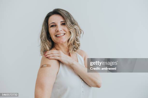 portrait of a mature woman showing that she has been immunized with the vaccine - vaccination imagens e fotografias de stock