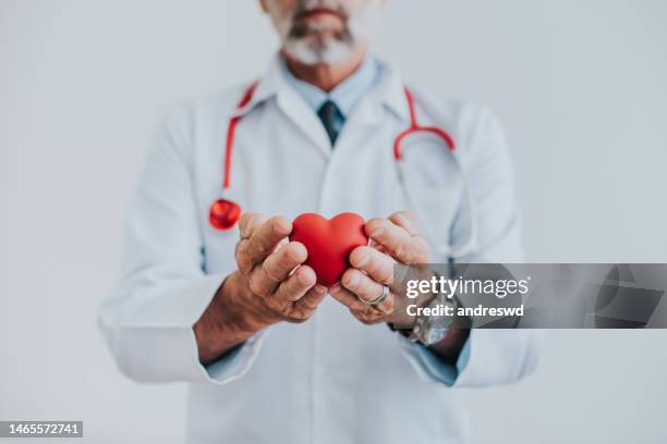 portrait of a doctor holding a heart in his hands - donation stock pictures, royalty-free photos & images