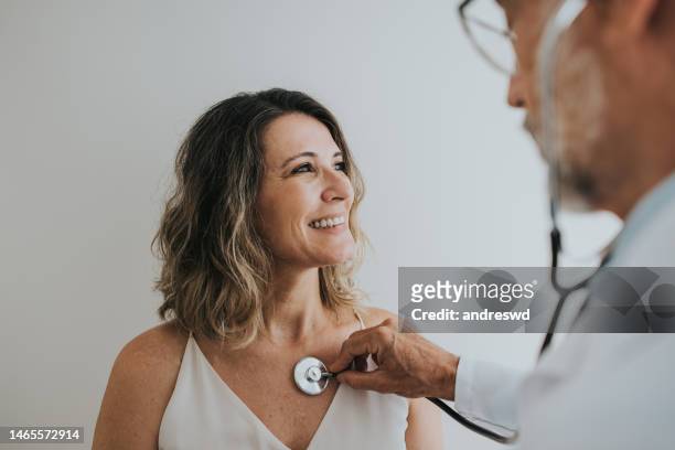docteur écoutant le coeur du patient avec le stéthoscope - adult patient with doctor and stethoscope photos et images de collection