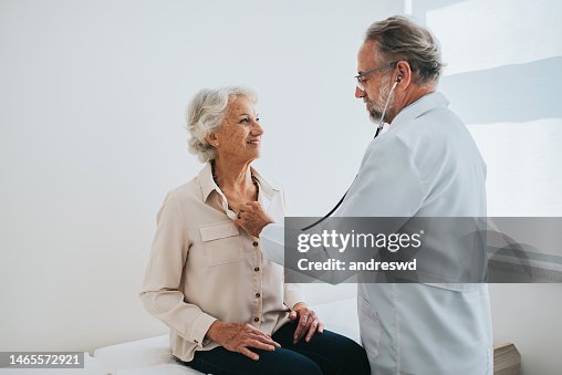 Médico que ouve os batimentos cardíacos do paciente da mulher sênior Médico que ouve os batimentos cardíacos do paciente da mulher sênior