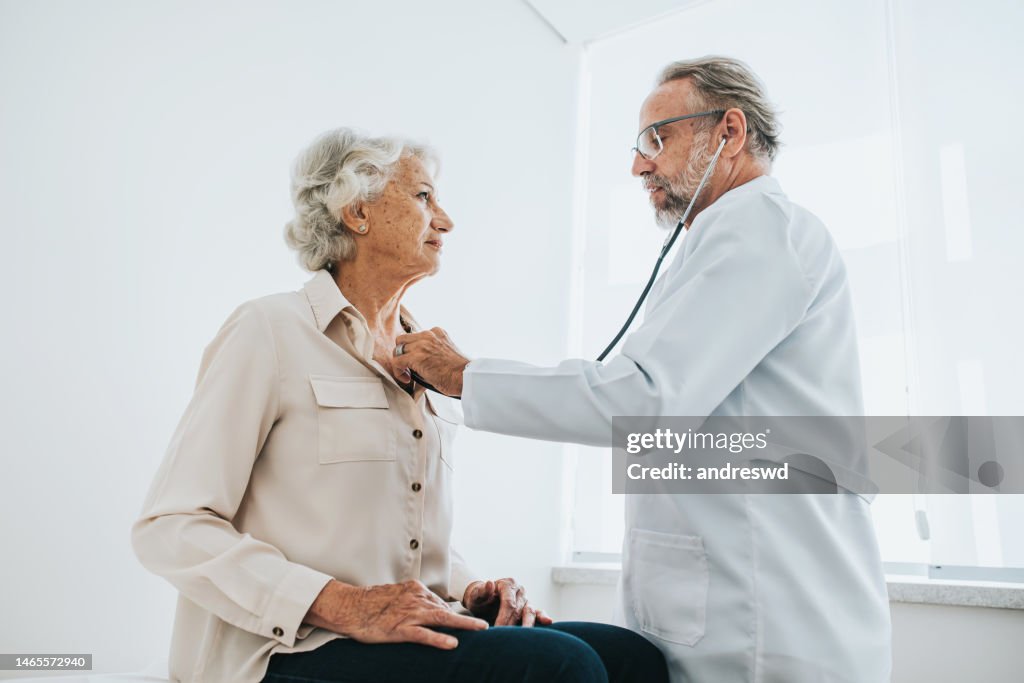 Doctor listening to senior woman patient heartbeat
