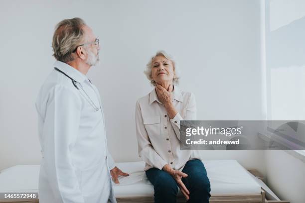 senior-patient mit halsschmerzen, ärztliche konsultation - white hair stock-fotos und bilder