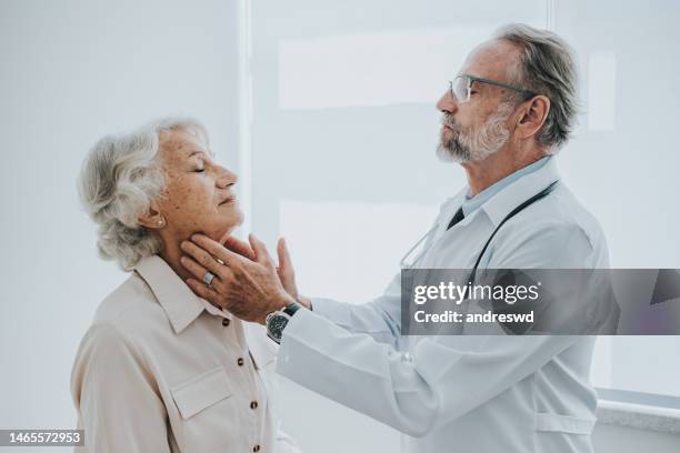 senior-patient mit halsschmerzen, ärztliche konsultation - white hair stock-fotos und bilder