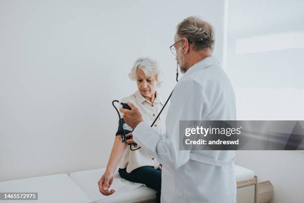 älterer patient misst den blutdruck im arm - hypertension stock-fotos und bilder