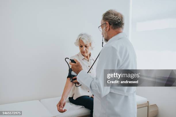 paciente mayor midiendo la presión arterial en el brazo - hipertenso fotografías e imágenes de stock