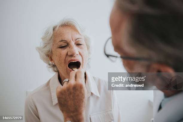 senior patient with tongue stick sore throat - man open mouth stock pictures, royalty-free photos & images
