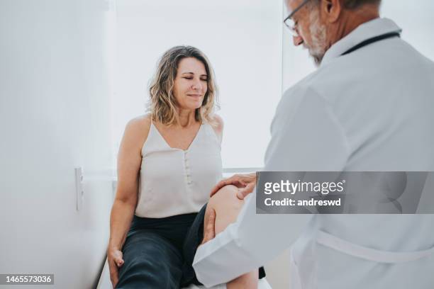 patient with knee pain in doctor's office - latina legs stockfoto's en -beelden