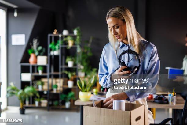 portrait of smiling young woman unpacking at her new desk after getting hired - farewell colleague stock pictures, royalty-free photos & images