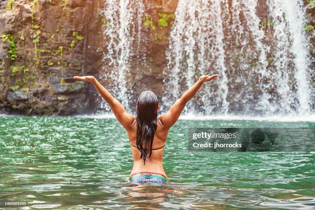 Young Hawaiian Woman Wading in Pool Near Remote Hawaiian Waterfall