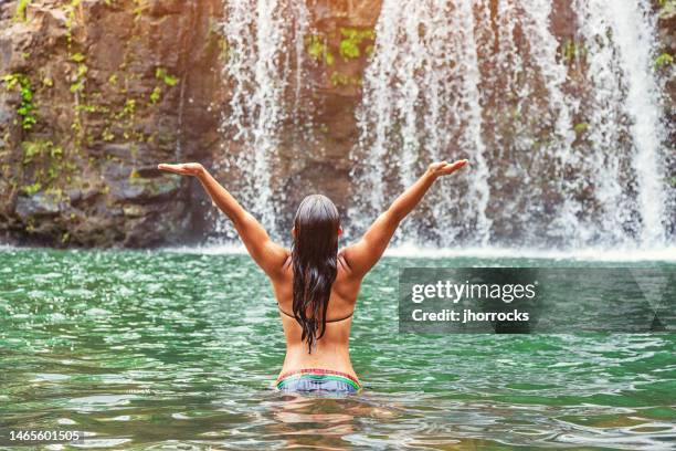 young hawaiian woman wading in pool near remote hawaiian waterfall - hawaiian waterfalls 個照片及圖片檔