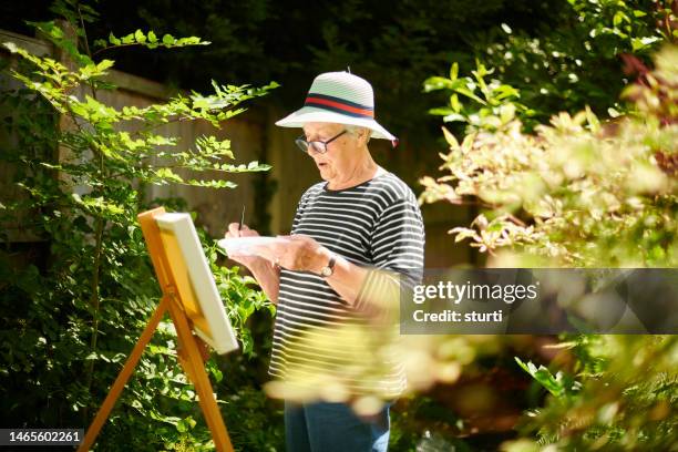 senior woman painting in the garden - craft supplies stock pictures, royalty-free photos & images