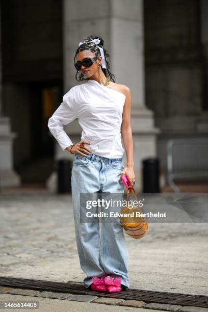 Guest wears a white ribbon knot in the hair, black sunglasses, gold and purple pearls earrings, a gold large chain necklace, a white asymmetric...