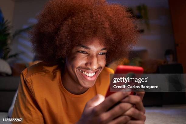 young man at home using cellphone watching social media apps. - smartphone video stock pictures, royalty-free photos & images