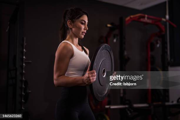 giovane donna atletica che esercita in palestra - sollevamento pesi femminile foto e immagini stock