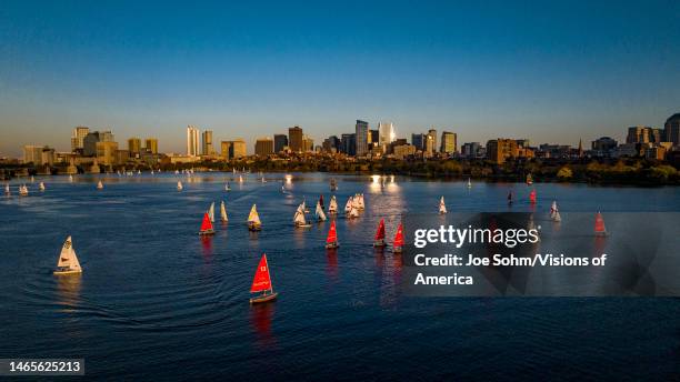 Sail boats on the Charles River in front of the dramatic Boston skyline at sunset, Massachusetts.