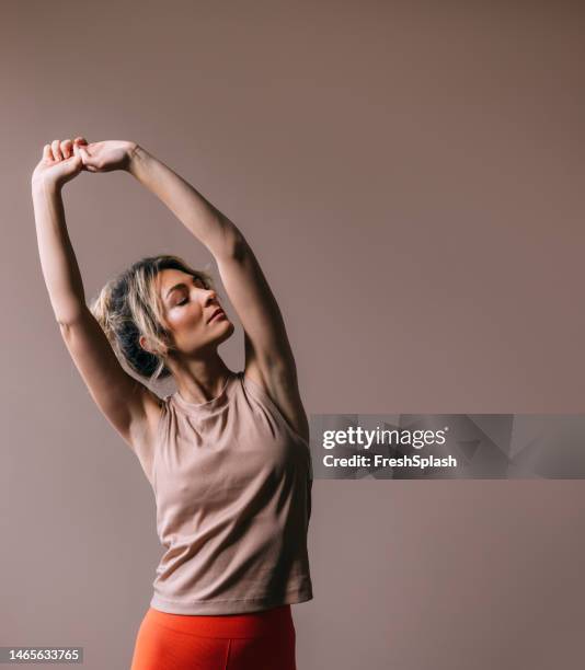 eine glückliche, schöne blonde sportlerin, die sich beim training dehnt - sportlerin stock-fotos und bilder